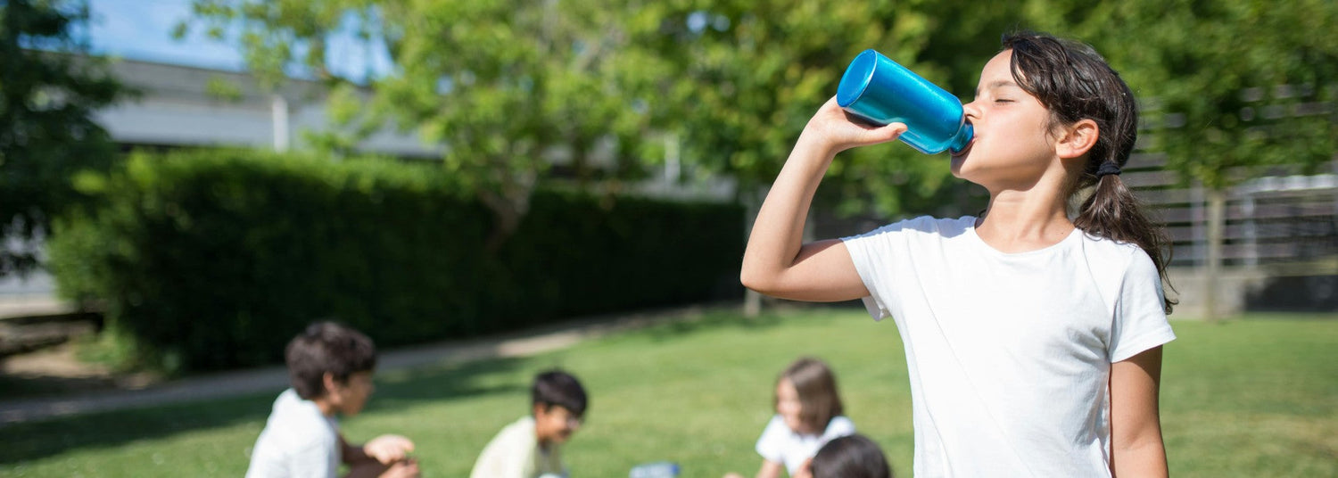 girl drinking water with other kids in a park