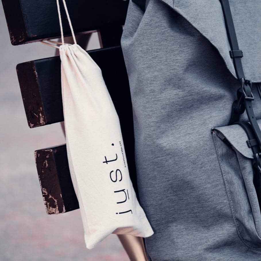 cotton bottle bag next to grey backpack on park bench