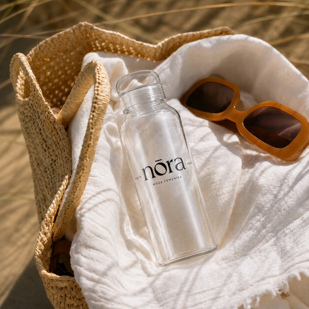 500ml (16oz) Glass water bottle with custom branding in a beach bag next to sunglasses