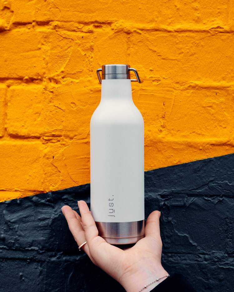 beautifully designed white reusable water bottle with stainless steel handle being carried in hand