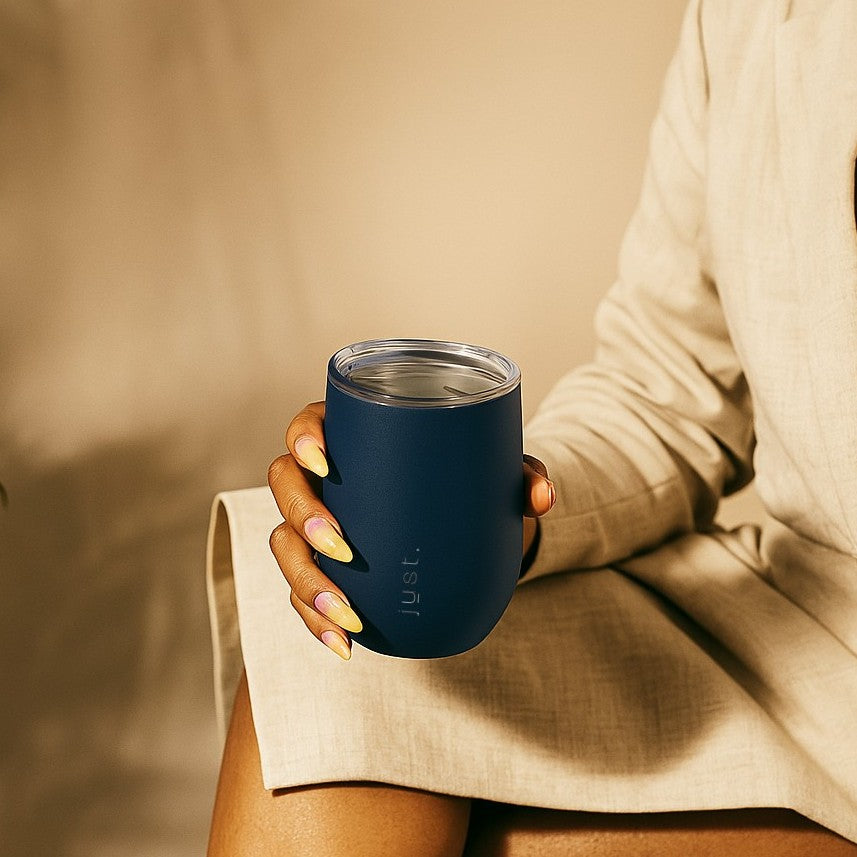 Person holding a blue insulated tumbler with a neutral background