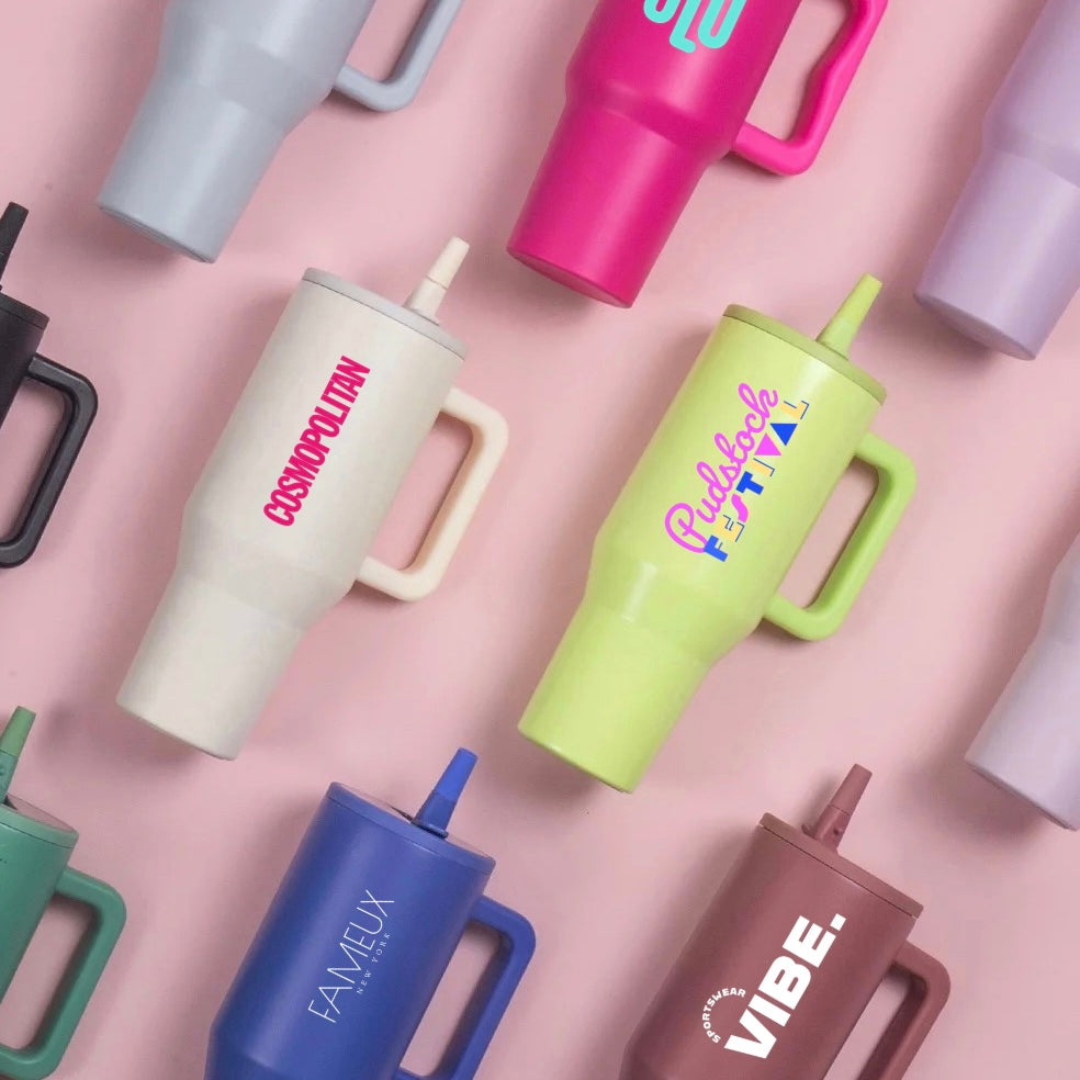 Colorful tumblers from Just Bottle with various designs and print on a pink background