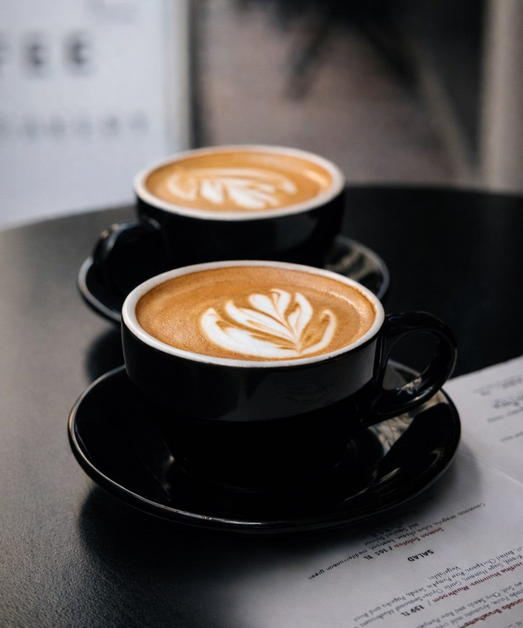 Two black porcelain cafe cups on a dark table