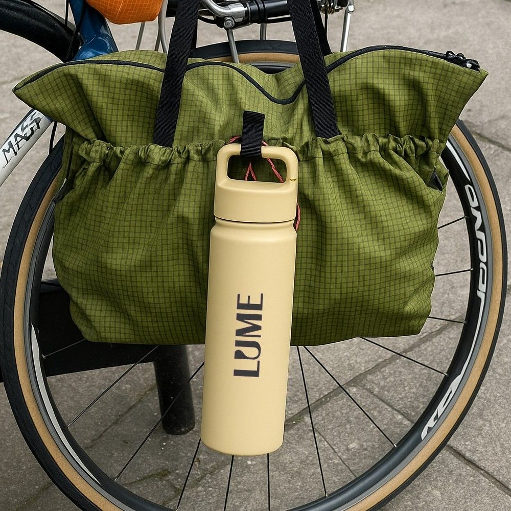 Green bag attached to a bicycle with a beige company logo water bottle by Just Bottle.