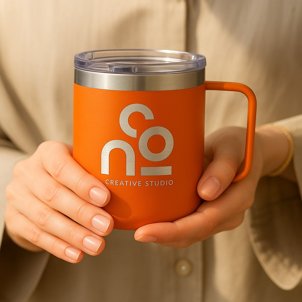 Orange mug with 'nO Creative Studio' logo held by a person wearing a beige jacket.