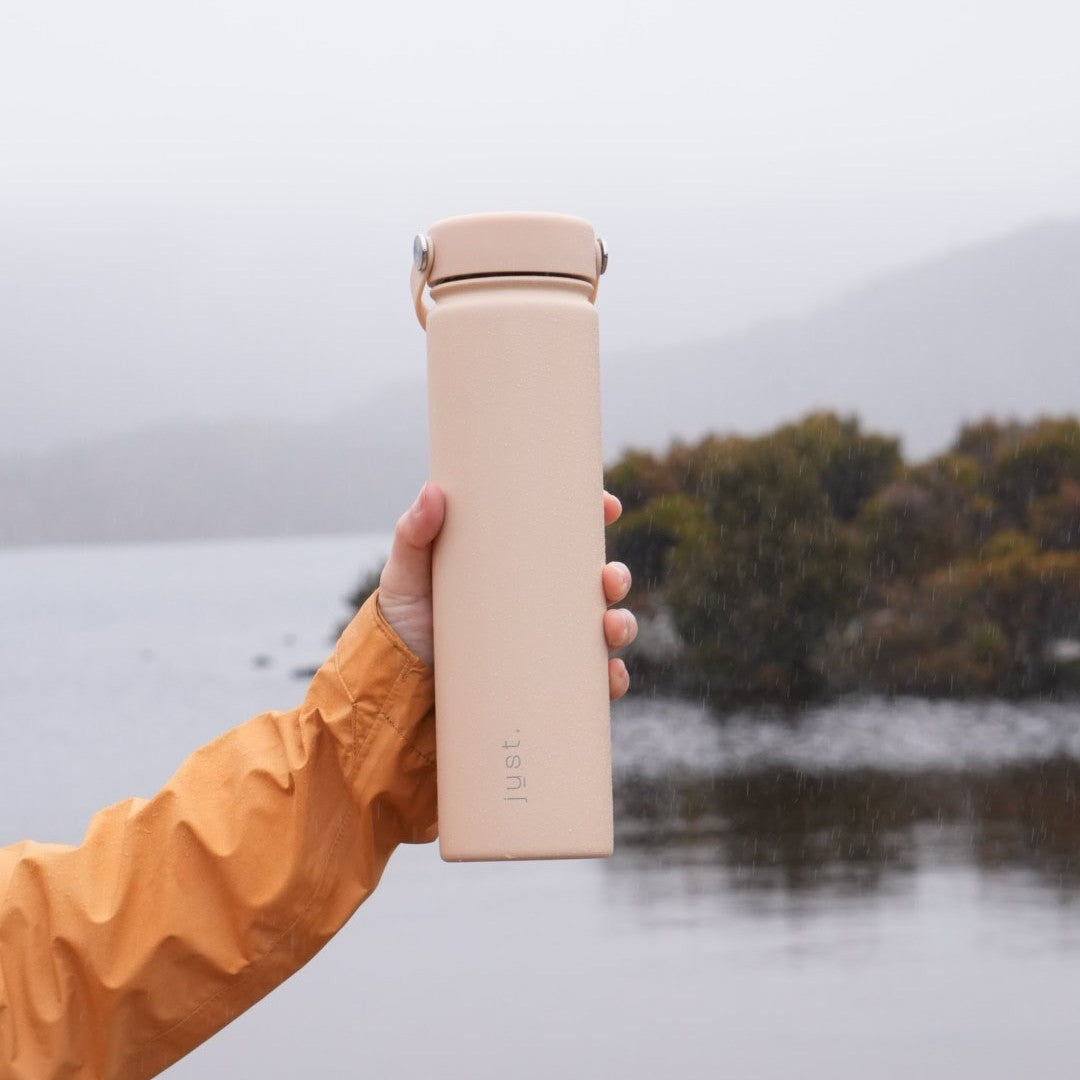 person holding a tall metal water bottle in the rain