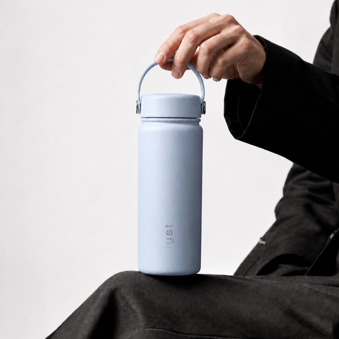 Person holding a Just Bottle light blue reusable water bottle