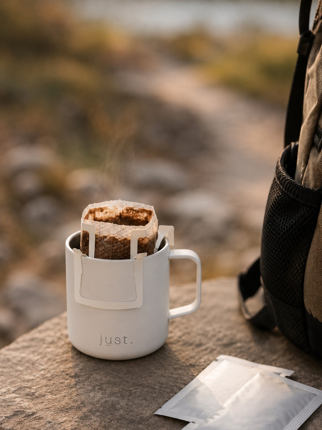 White 10oz insulated camp mug with a coffee filter on a rock, with a blurred natural background