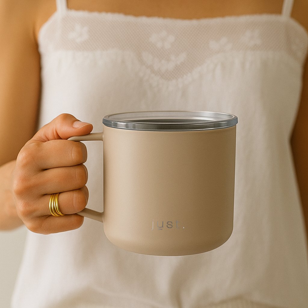 Person holding a beige mug wearing a white lace top.
