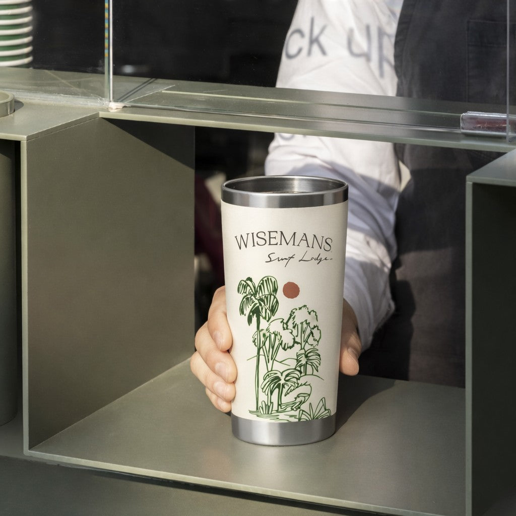 Person holding a 'Wisemans' branded metal travel tumbler with a plant design.