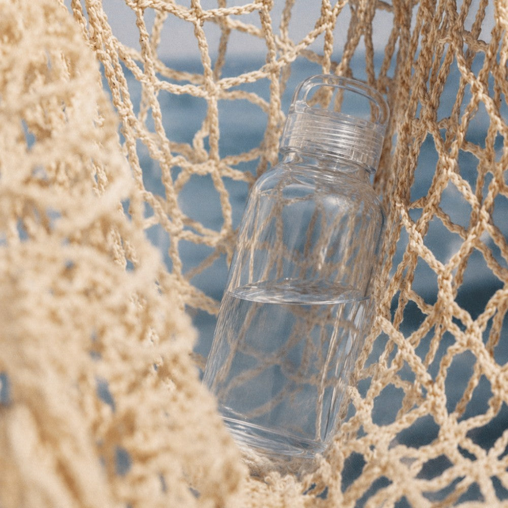 300ml clear glass bottle inside a brown net with ocean in the background