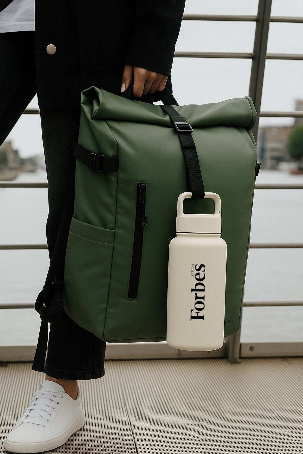 Person holding a green backpack with a white 'Forbes' company logo water bottle - Just Bottle