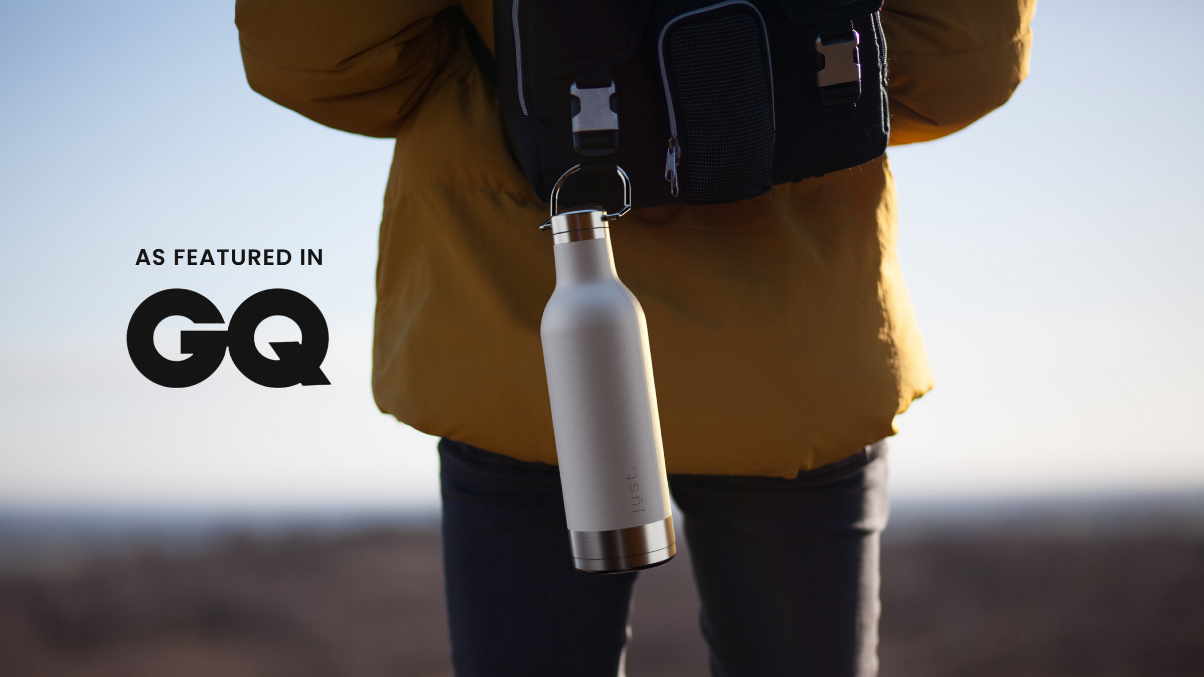 white stainless steel water bottle hanging from backpack with man in yellow jacket