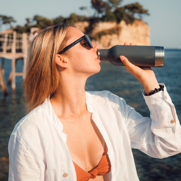 person on travel drinking from reusable water bottle outdoors