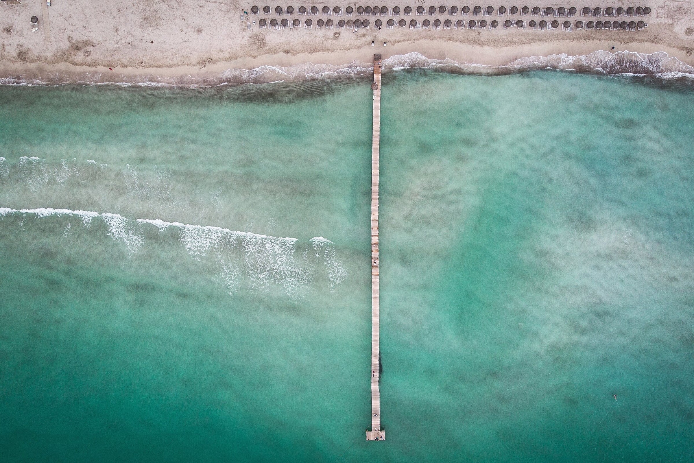 Teal ocean image with beach and umbrellas