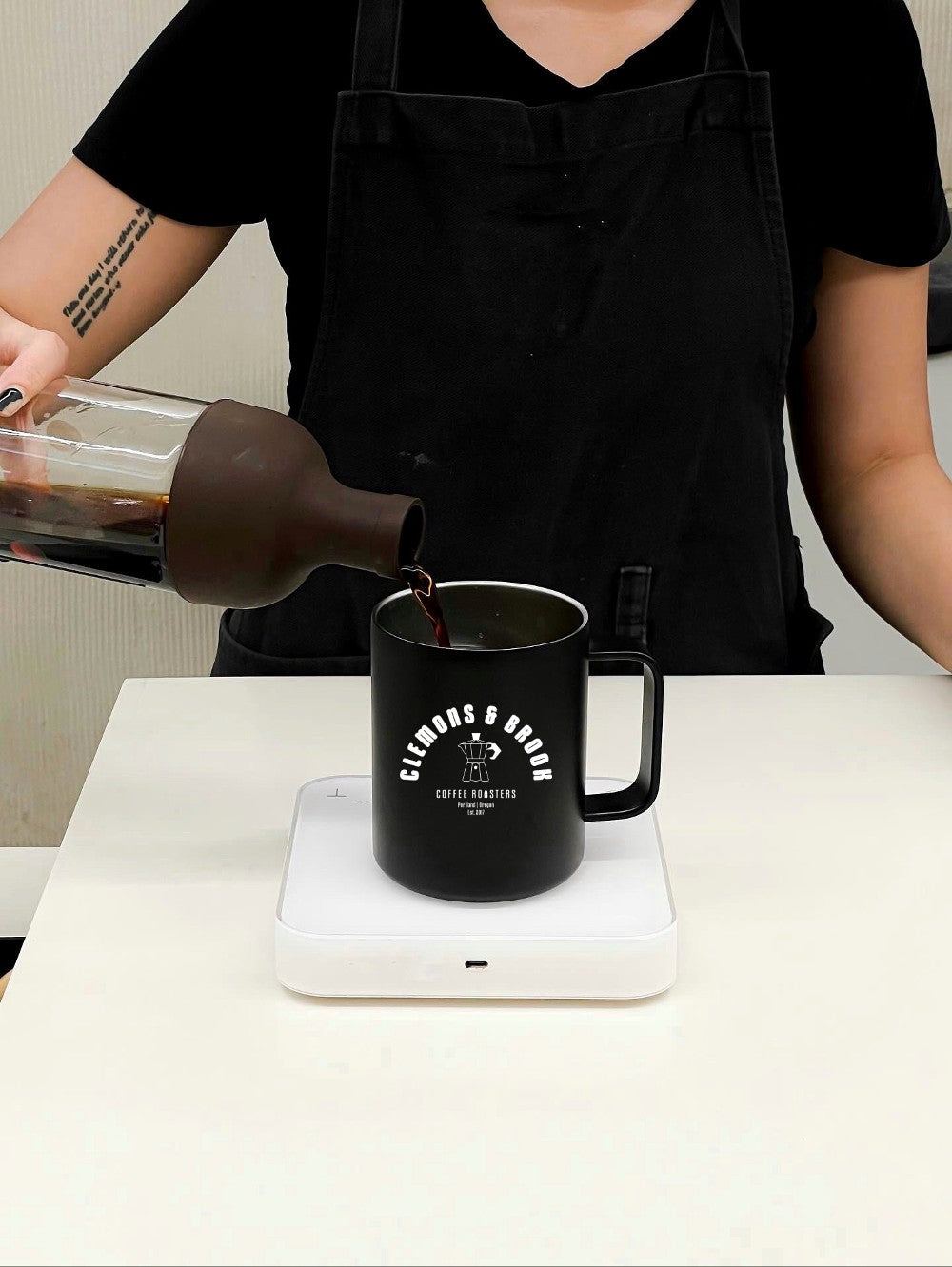 Barista pouring coffee into Black stainless steel mug