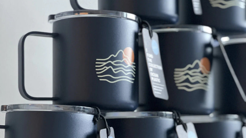 blue reusable coffee mugs with a company logo stacked on top of each other