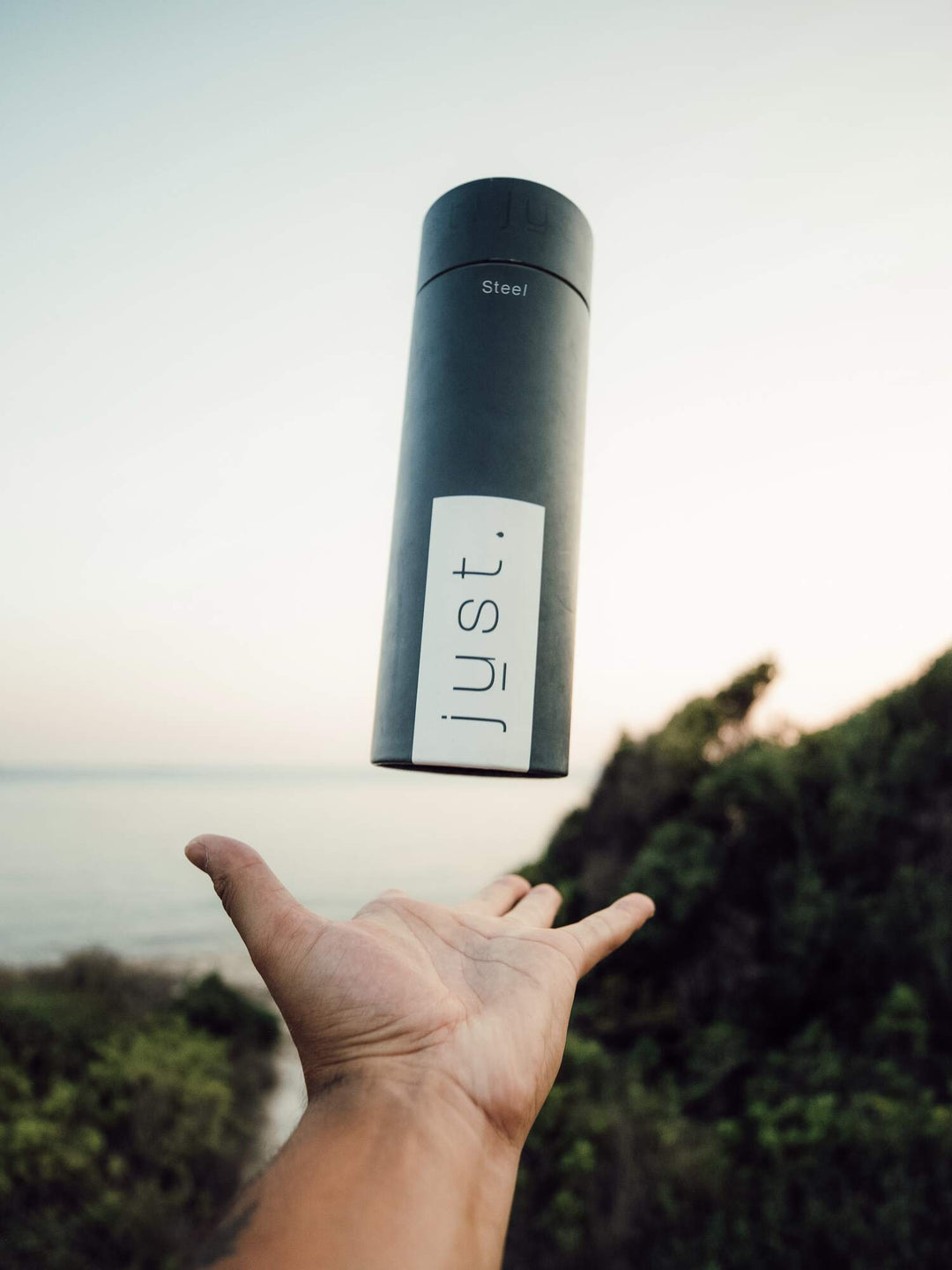 grey recyclable gifting tube packaging with ocean in background