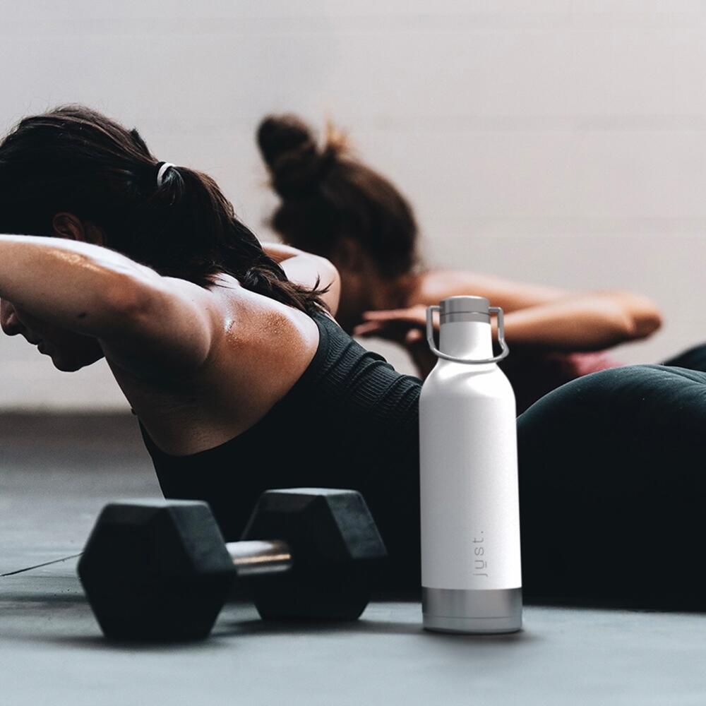 glacier just bottle in front of lady doing back exercise on a black yoga matt