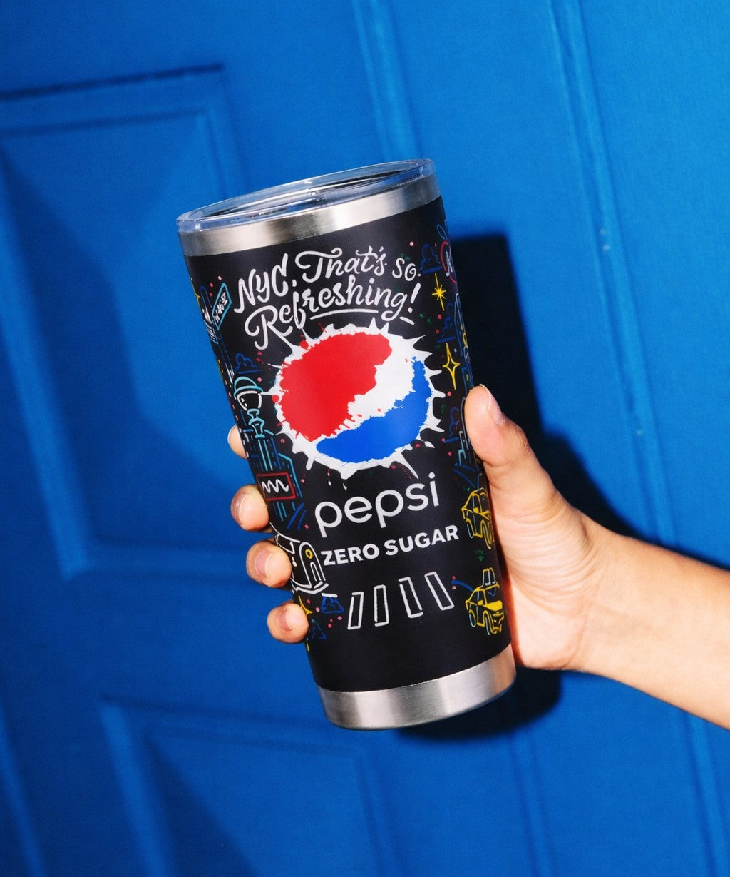Person holding a Pepsi Zero Sugar travel tumbler against a blue background