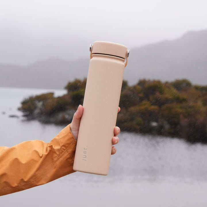 Holding a 25oz (750ml) reusable water bottle in beige - keeps hands cold