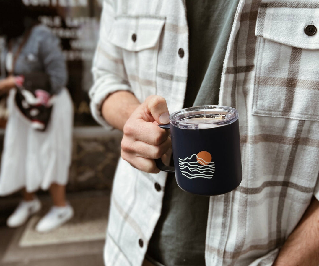 man holding Just Bottle slow sip mug in front of a cafe