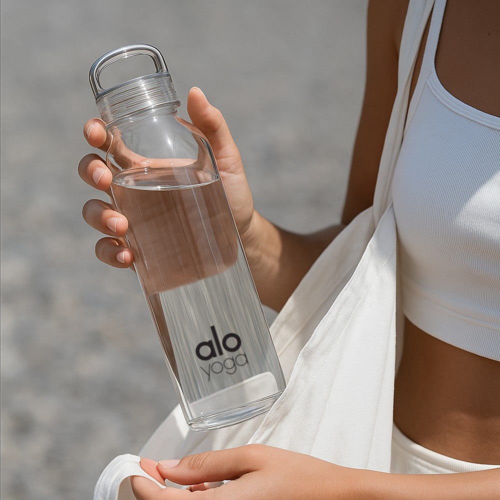 Person holding a tall glass reusable bottle with alo yoga company logo - Just Bottle