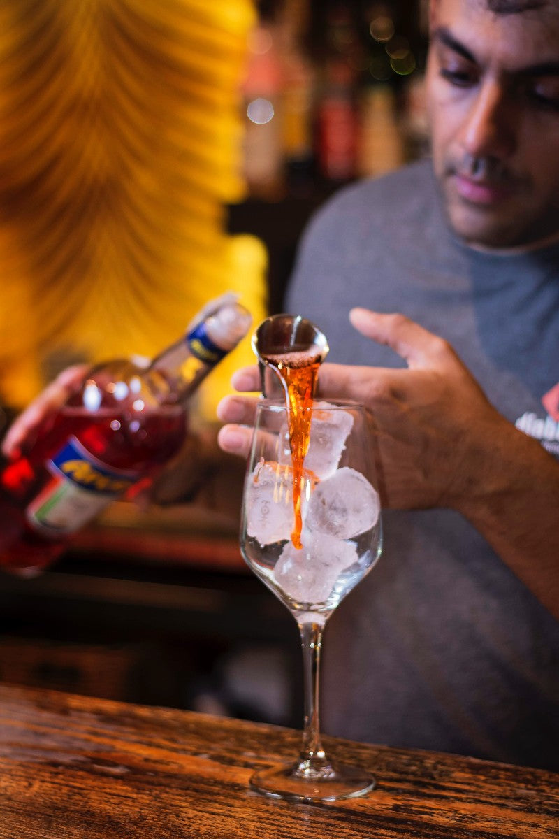 man pouring aperol into a glass with ice