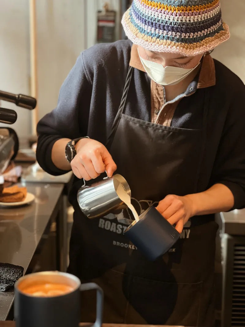 barista filling a blue mug with coffee