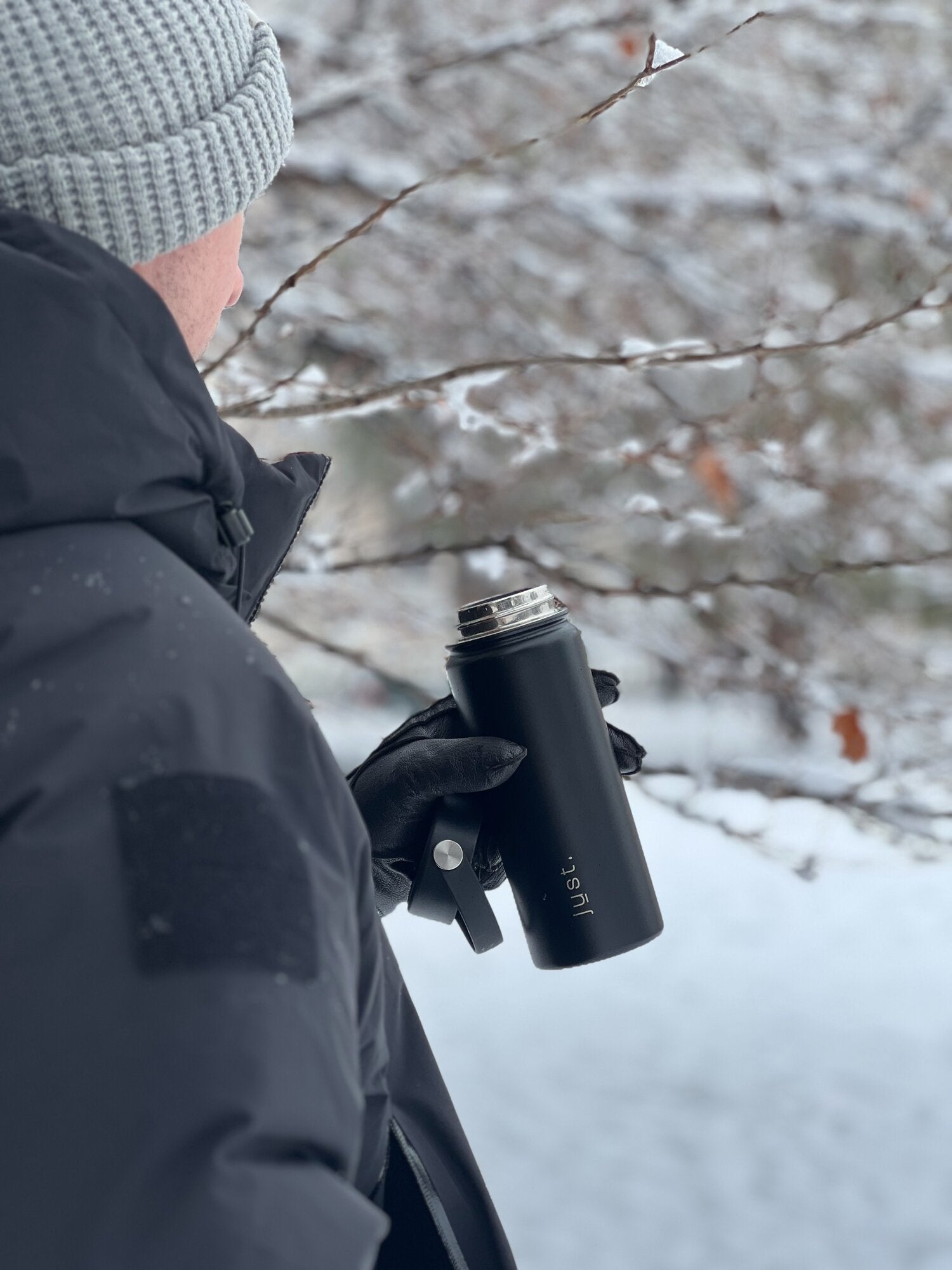 man holding black metal water bottle in the snow