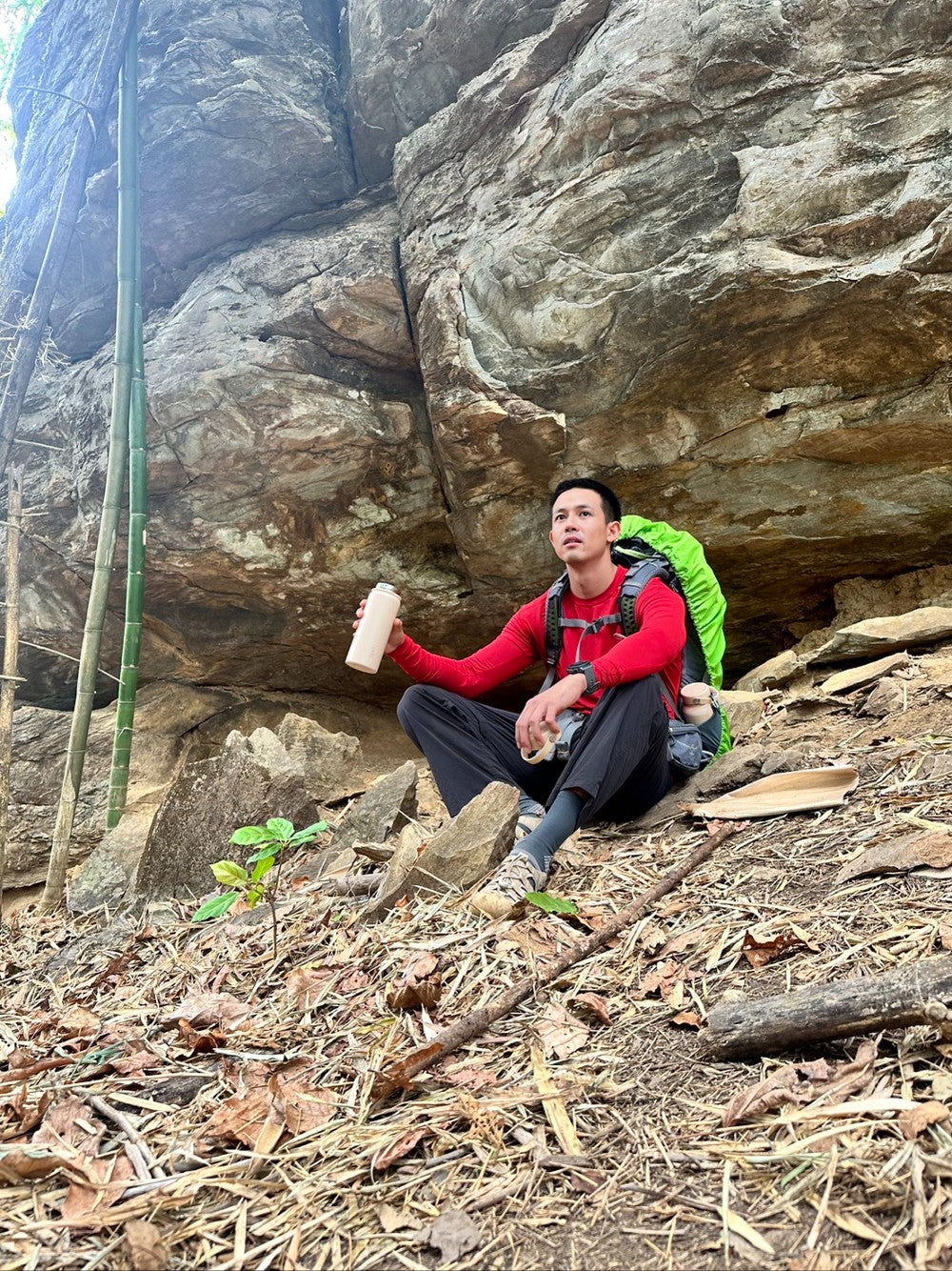 hiker with beige reusable bottle sitting on a rock