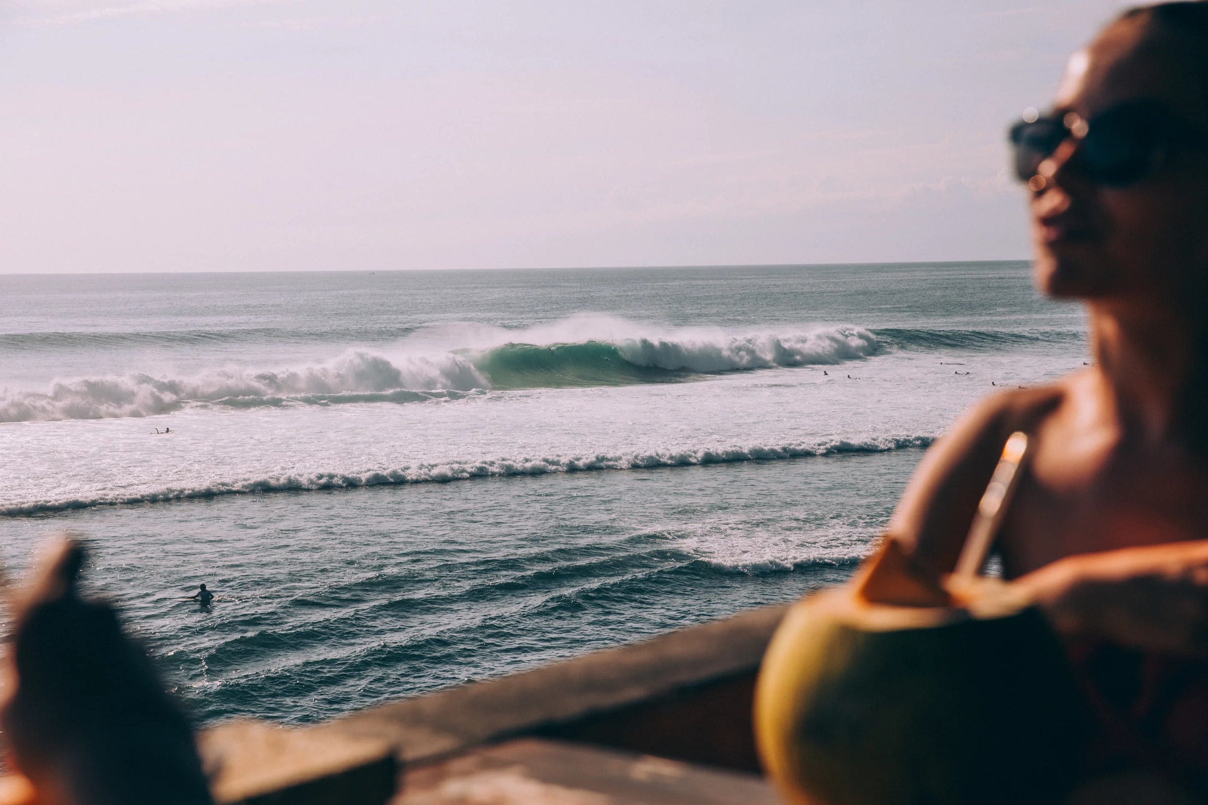 crashing ocean waves behind woman sitting at a beach bar