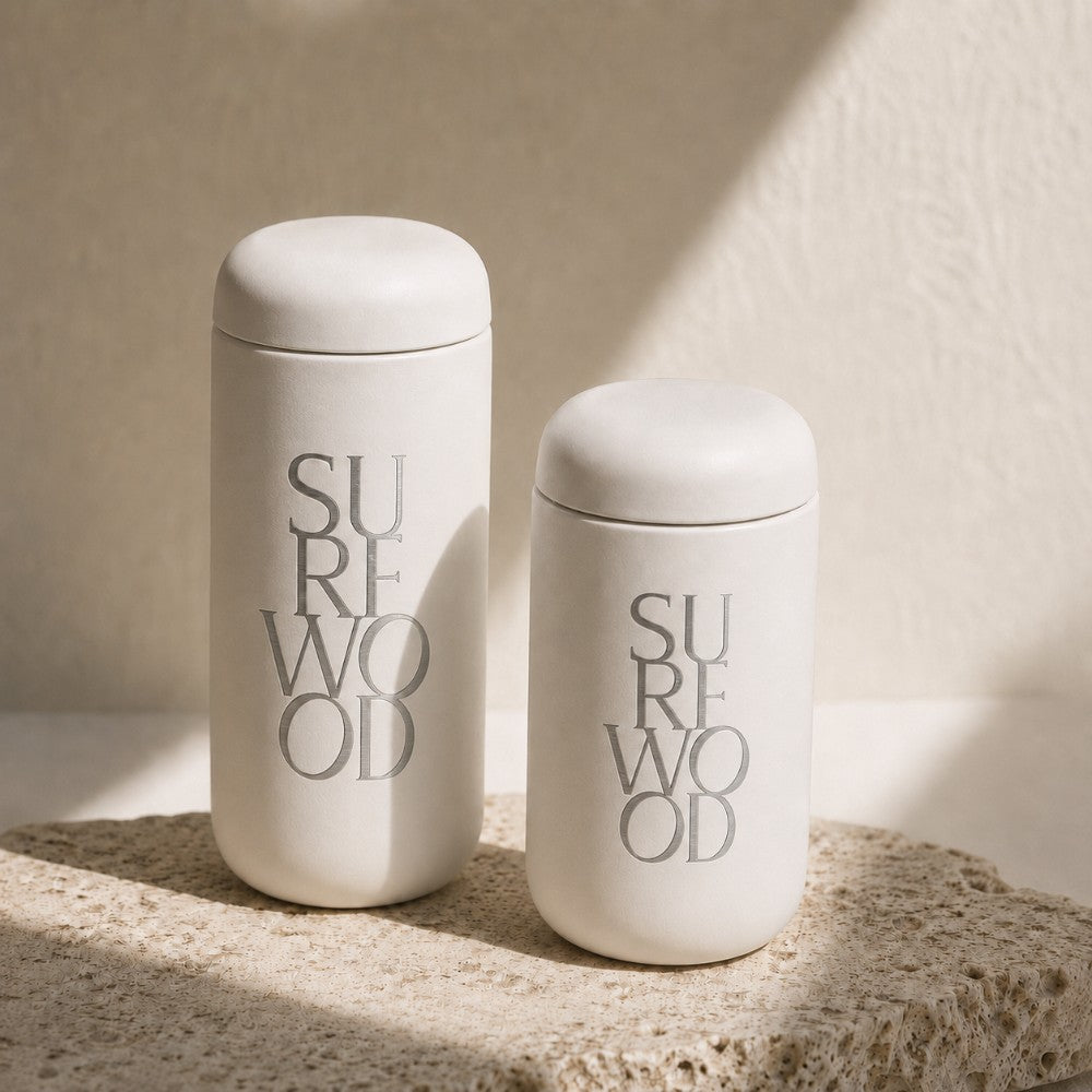 Two laser engraved custom logo leakproof tumblers on a rock in front of a white wall