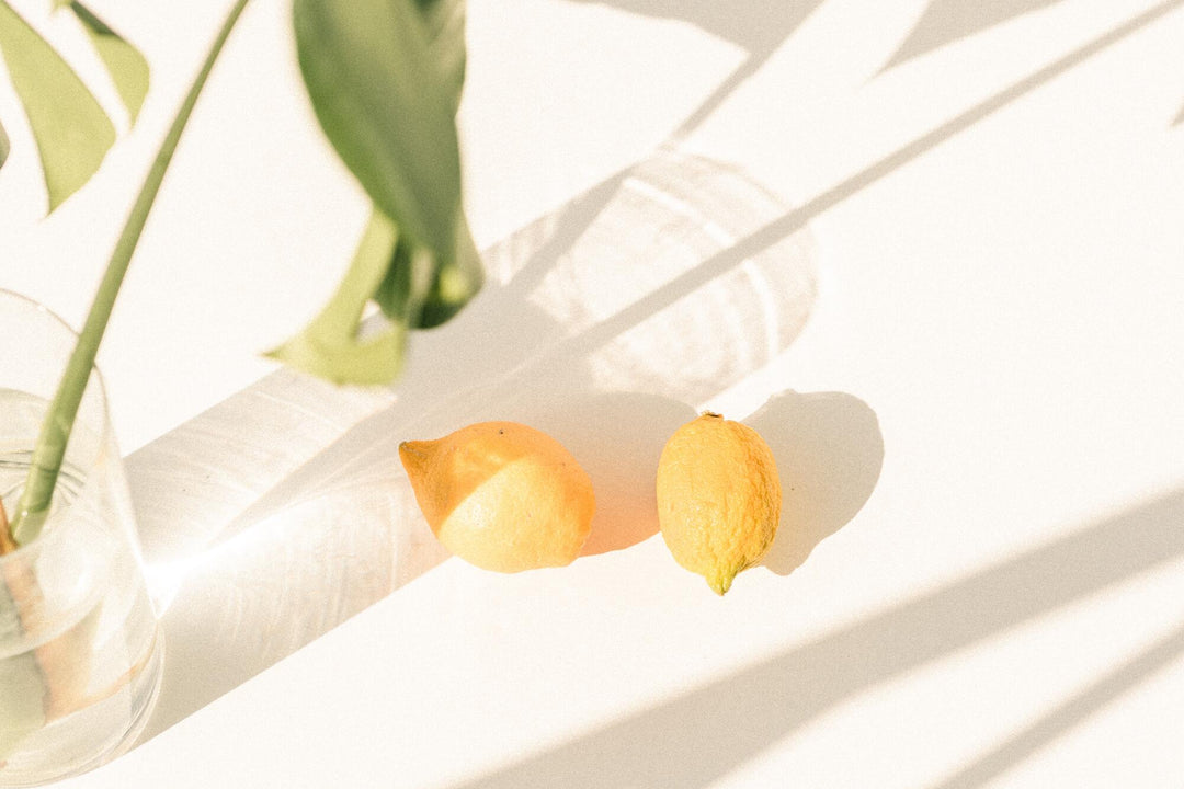 two lemons on a table next to a plant