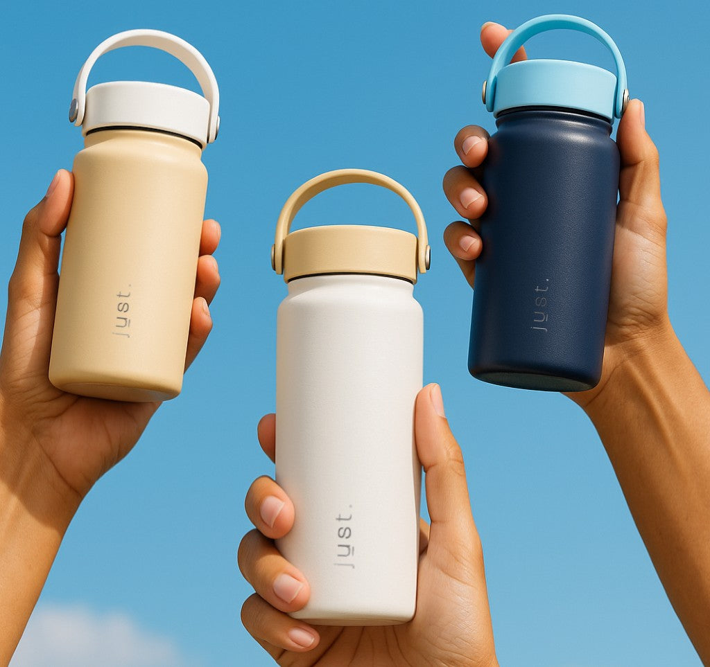 Three hands holding different colored Just water bottles against a clear blue sky.
