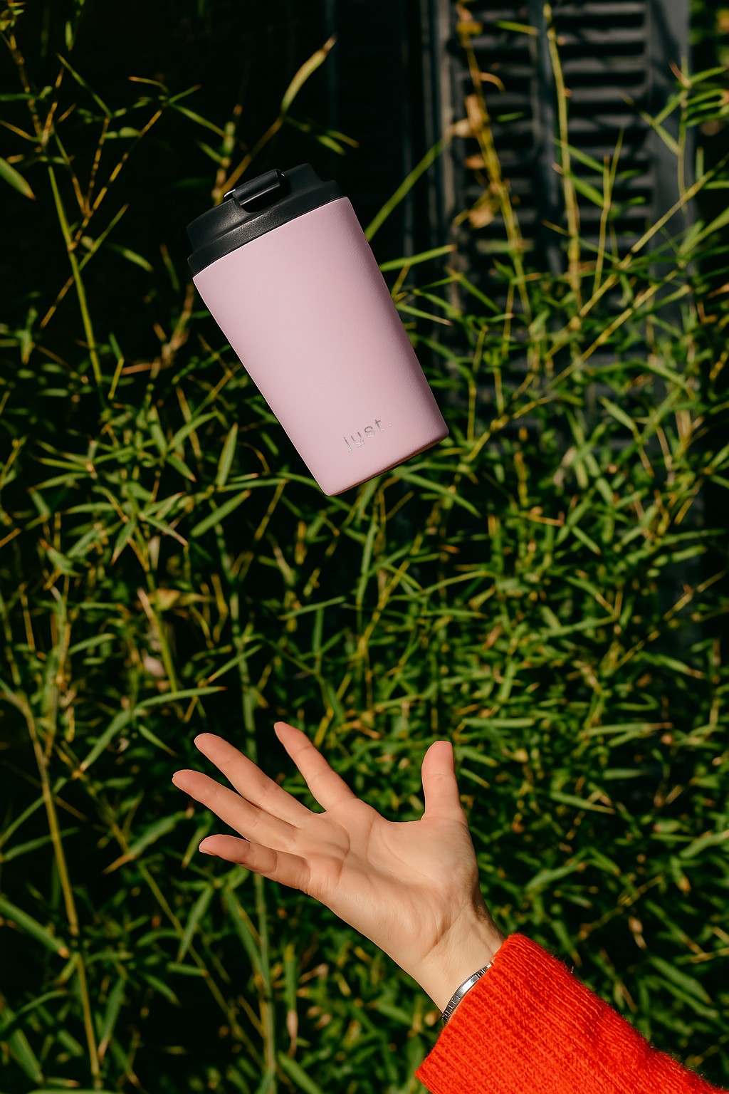 someone throwing a pink coffee cup in the air