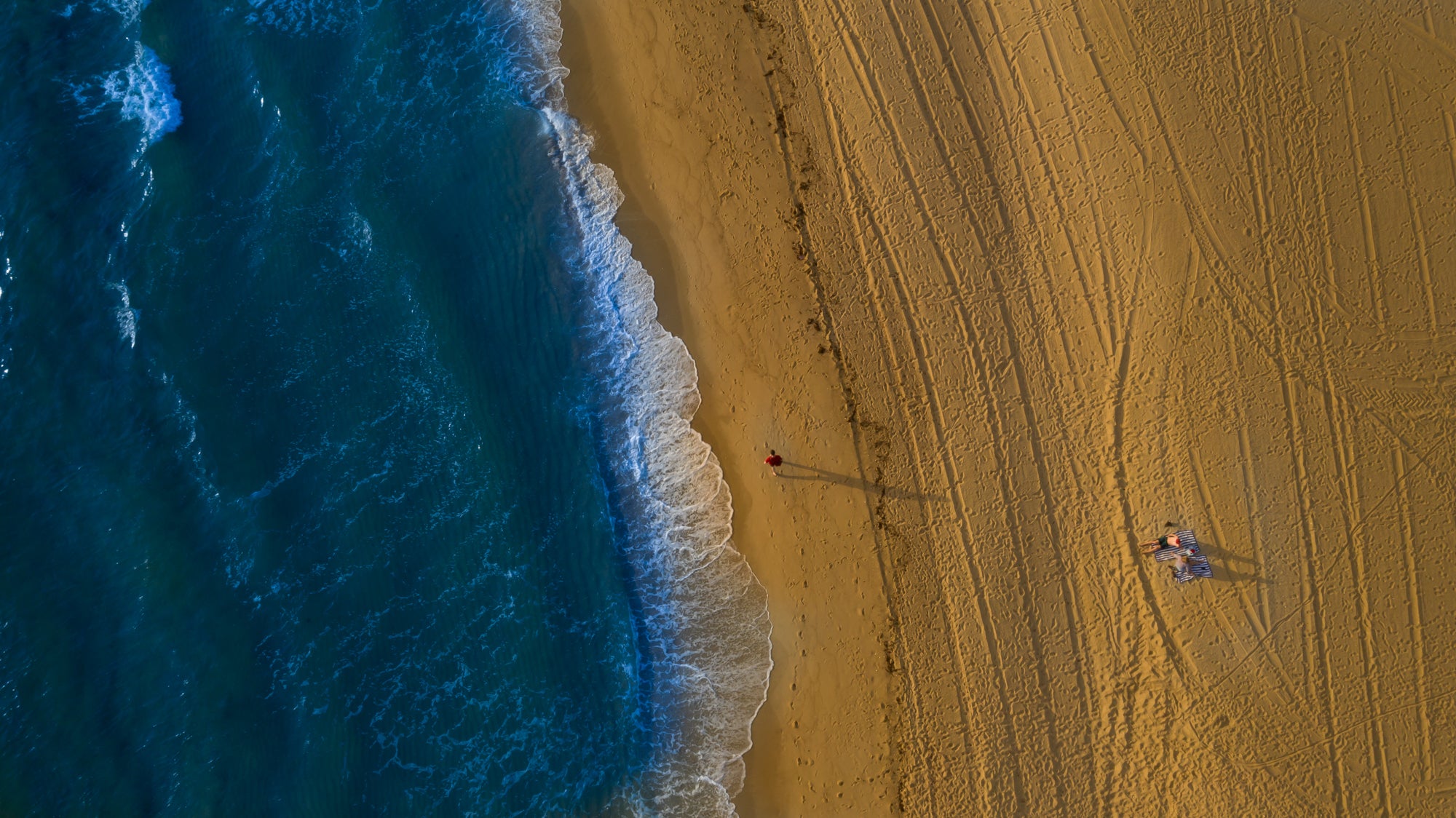 couple lying on a clean beach next to the ocean