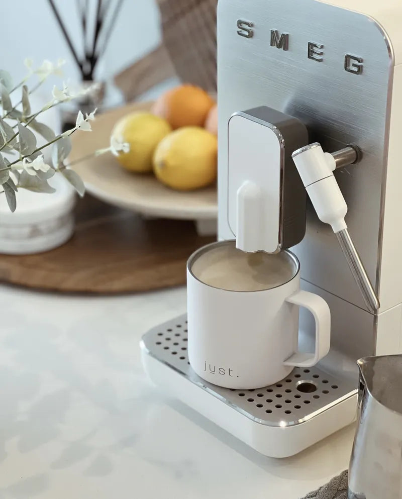 white reusable coffee mug under coffee machine