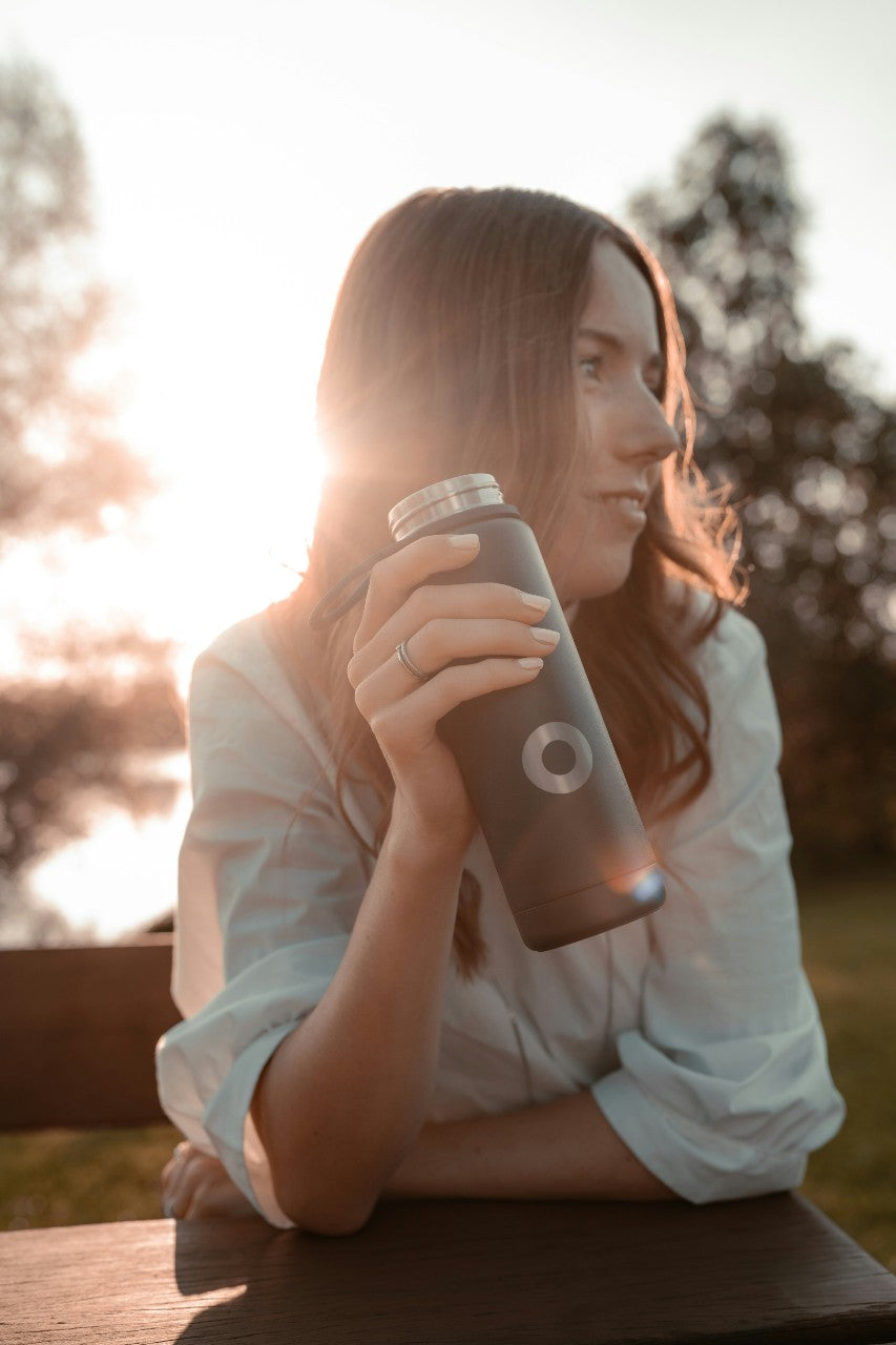 woman holding bottle sitting on bench